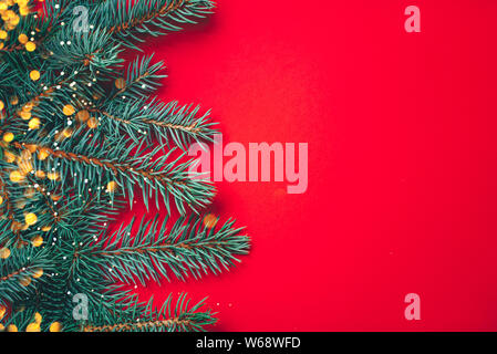 Fir branches with blurred lights garland on a red background. Stock Photo