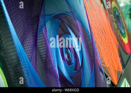 Closeup of a hand-made article made of multi-colored threads stretched over a frame, abstraction in violet tones, selective focus Stock Photo