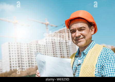 Male builder, architect or engineer in a helmet and glasses on a construction site. Stock Photo