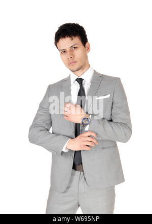 A young handsome business man standing in the studio in a light gray suit, thinking, looking into the camera, isolated for white background Stock Photo