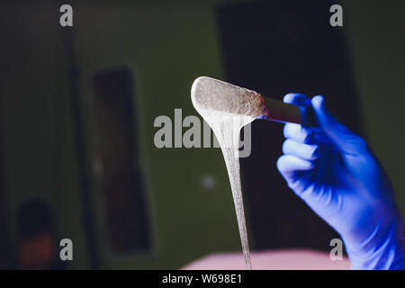 depilation and beauty concept - sugar paste or wax honey for hair removing with wooden waxing spatula sticks. Stock Photo