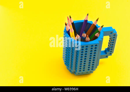 Colored pencils in a bucket on yellow background. Back to scool concept. Stock Photo