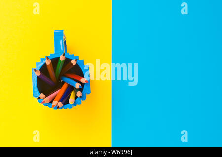 Colored pencils in a bucket on blue and yellow background. Back to scool concept. Stock Photo