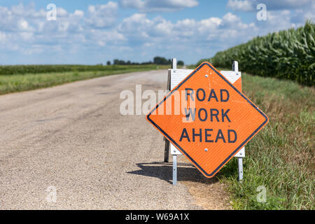 Road work ahead sign on barricade on rural country asphalt road Stock Photo