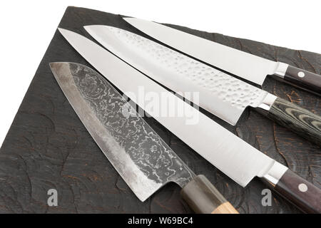 Four different kitchen knives on black cutting board Stock Photo