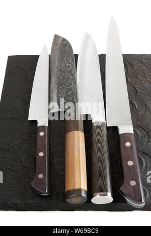 Four different knives on black wooden cutting board Stock Photo