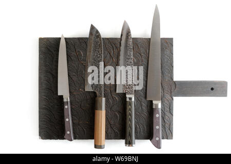 Four different knives on black cutting board, isolated on white with shadows Stock Photo