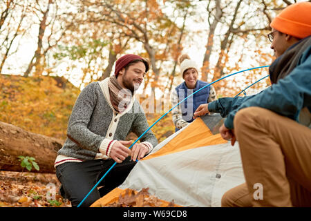 Group of Canadian hikers setting up a tent in a fall forrest Stock Photo