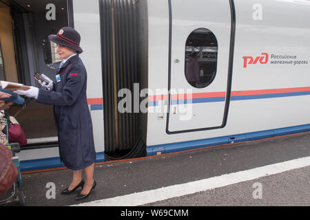 Saint Petersburg, Russia - June 06, 2017: an uniformed attendant orients passengers boarding the high speed train from Saint Petersburg to Moscow Stock Photo