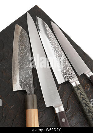 Four different knives on black wooden board, fragment Stock Photo