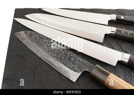 Four different knives on black wooden cutting board Stock Photo