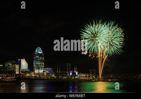 Fireworks launch from a barge in the Ohio River in Cincinnati, Ohio, USA, against the Cincinnati cityscape, including Great American Ball Park. Stock Photo