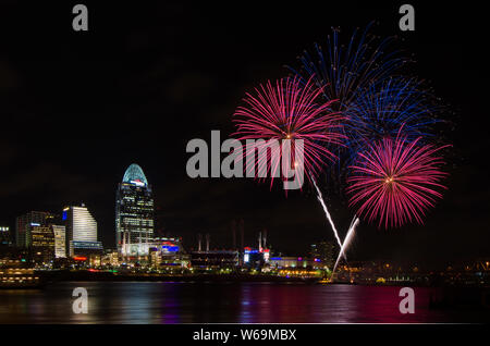 Fireworks launch from a barge in the Ohio River in Cincinnati, Ohio, USA, against the Cincinnati cityscape, including Great American Ball Park. Stock Photo