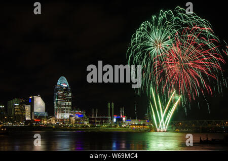 Fireworks launch from a barge in the Ohio River in Cincinnati, Ohio, USA, against the Cincinnati cityscape, including Great American Ball Park. Stock Photo