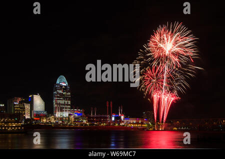 Fireworks launch from a barge in the Ohio River in Cincinnati, Ohio, USA, against the Cincinnati cityscape, including Great American Ball Park. Stock Photo