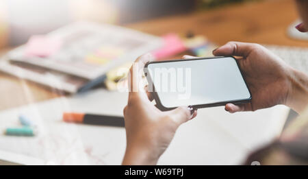 Close-up view of female fashion designer hand's searching for new ideas with blank screen smartphone to improve her spring collection Stock Photo