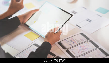 UI designer discussing on interface project while using tablet Stock Photo