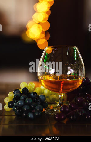 French grape brandy, strong alcoholic drink. Still life. Glass of cognac and bunch of grapes. Service and tasting concept. Stock Photo