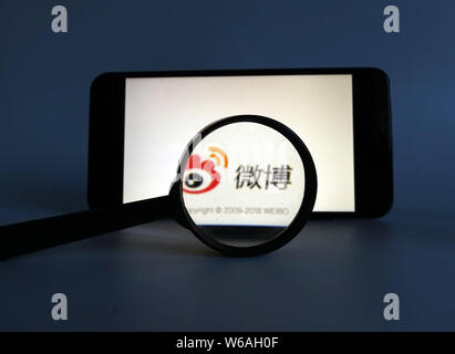 --FILE--A Chinese netizen looks at a logo of Weibo, the Twitter-like microblogging service of Chinese Internet portal Sina, on his smartphone in Ji'na Stock Photo