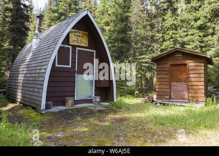 Old Backcountry Ranger Wood Log Cabin and Outhouse in Forest Meadow Clearing. Hiking Redearth Creek, Banff National Park, Canadian Rocky Mountains Stock Photo