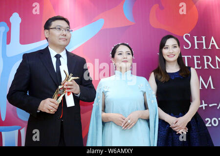 Batbayar Chogsom, left, director of 'Out of Paradise', wins the Best Feature Film award at the awarding ceremony of the 21st Golden Goblet Awards duri Stock Photo