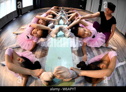 A Chinese teacher instructs young girls to stretch their legs and bend their bodies to learn dancing skills at a training center in Bozhou city, east Stock Photo