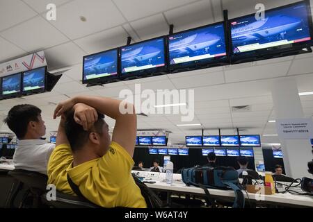 Journalists at the media center watch screens display that U.S. President Donald Trump deplanes as his Air Force One arrives at the Paya Lebar Air Bas