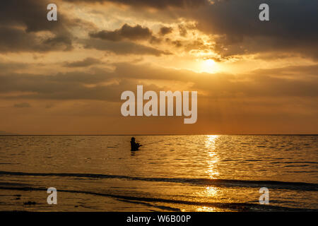 Silhouette of a fisherman at sunset at Lovina Beach, Buleleng, Bali, Indonesia. Stock Photo
