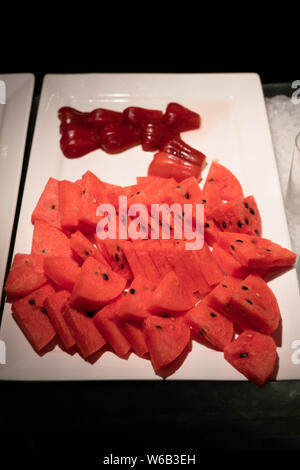Slices of watermelon and bell fruits on white plate Stock Photo