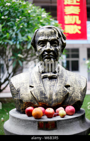 A bronze statue of American inventor Thomas Edison is embraced by apples and other fruits with blessings written by students on the surfaces to pray f Stock Photo