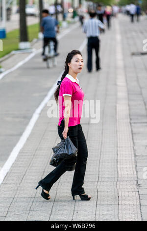 --FILE--A young North Korean woman wearing high heels walks on the street in Pyongyang, North Korea, 29 August 2016. Stock Photo