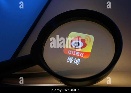 --FILE--A Chinese netizen looks at a logo of Weibo, the Twitter-like microblogging service of Chinese Internet portal Sina, on his smartphone in Ji'na Stock Photo