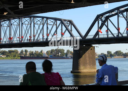 Tourists look far into the distance over Sinuiju of North Korea on the other side of Yalu River, also called the Amrok River or Amnok River, on the bo Stock Photo