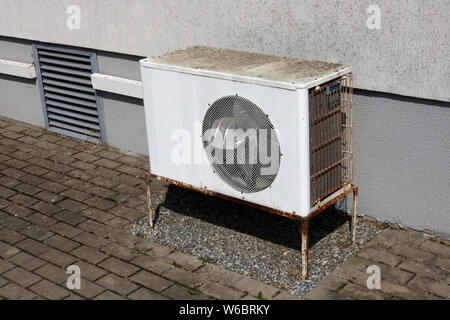 Old rusty aged air conditioner installed near the wall of a village house Stock Photo