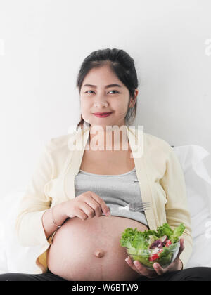 Asian pregnant woman eating fruit salad, lifestyle concept. Stock Photo