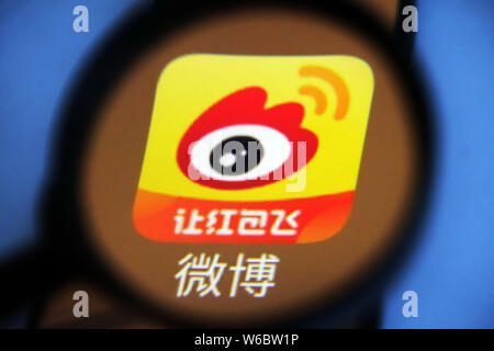 --FILE--A Chinese netizen looks at a logo of Weibo, the Twitter-like microblogging service of Chinese Internet portal Sina, on his smartphone in Ji'na Stock Photo