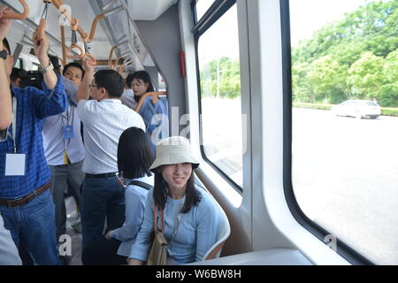 Passengers take a railless train, developed by the CRRC Zhuzhou Institute Co. Ltd, on the world's first ART (Autonomous Rail Rapid Transit) A1 line in Stock Photo