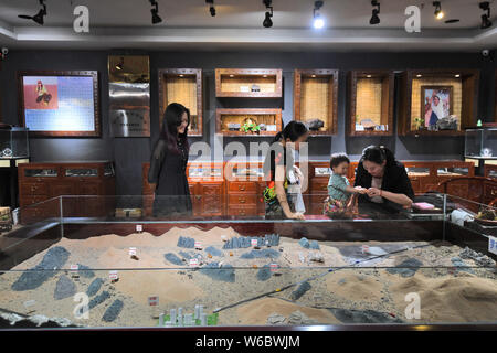 Chinese woman Yang Kexin of Miao ethnic group introduces an artwork made of aerolite to customers at her science museum to introduce meteorite culture Stock Photo