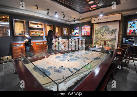 Chinese woman Yang Kexin of Miao ethnic group introduces an artwork made of aerolite to customers at her science museum to introduce meteorite culture Stock Photo