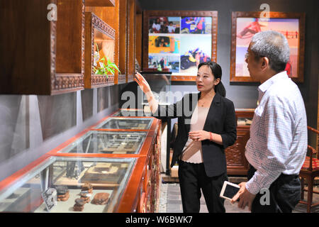 Chinese woman Yang Kexin of Miao ethnic group introduces an artwork made of aerolite to a customer at her science museum to introduce meteorite cultur Stock Photo