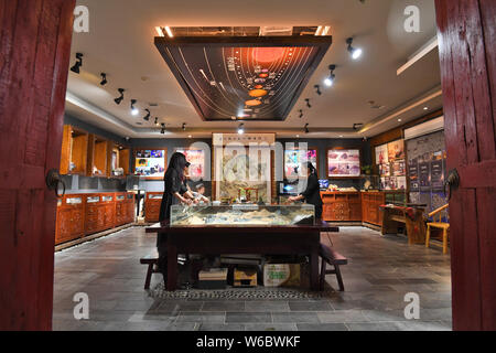 Chinese woman Yang Kexin of Miao ethnic group introduces an artwork made of aerolite to customers at her science museum to introduce meteorite culture Stock Photo