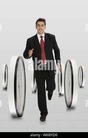 Businessman running with clocks Stock Photo