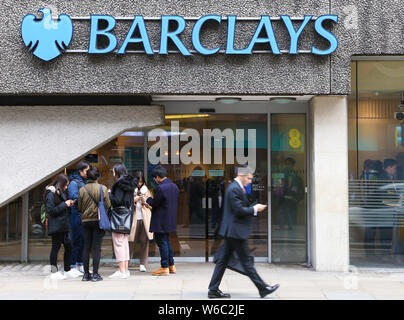 People walk past a branch of Barclays bank in London. Stock Photo