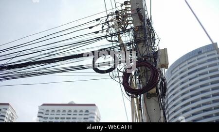 Messy wires attached to the electric pole, the chaos of cables and wires on an electric pole Thailand, concept of electricity. Stock Photo