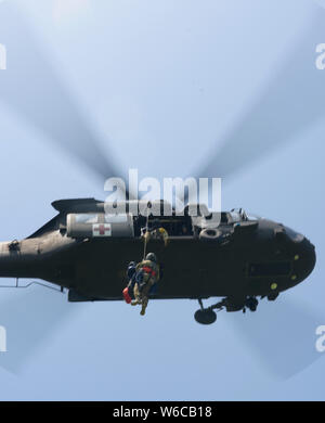 Members of the Indiana Helcopter Rescue Team are hoisted in to a UH-60 Black Hawk Helicopter at Kingsbury, Indiana july 23. The Indiana HART is a joint miliatary-civilian serach and rescue operation teaming Indiana Army National Guard aviation with South Bend Fire Department rescuers. Stock Photo