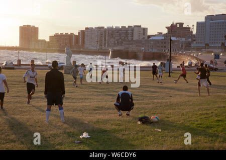People play football along the coastal road in Montevideo, Uruguay Stock Photo