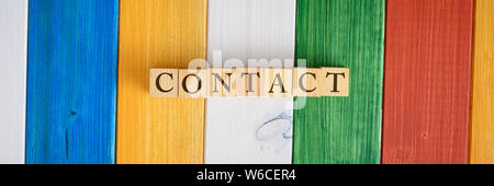 Contact text on wooden blocks over a background of colorful wooden boards. Stock Photo