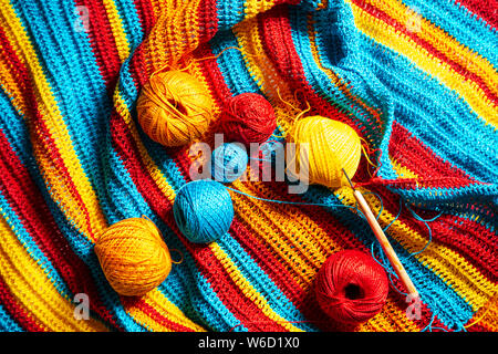 Multi-colored striped crochet, crochet hook and yarn. Handwork, hobby. Close-up, top view. Stock Photo