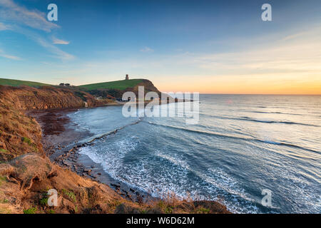 Sunset over the bay at Kimmeridge on Dorset's Jurassic Coast with Clavel's Tower in the distance Stock Photo