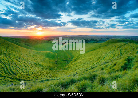 Dramatic sunset over The Manger on White Horse Hill at Uffington in Oxforshire with Dragon Hill on the left, it is on the Ridgeway long distance walki Stock Photo